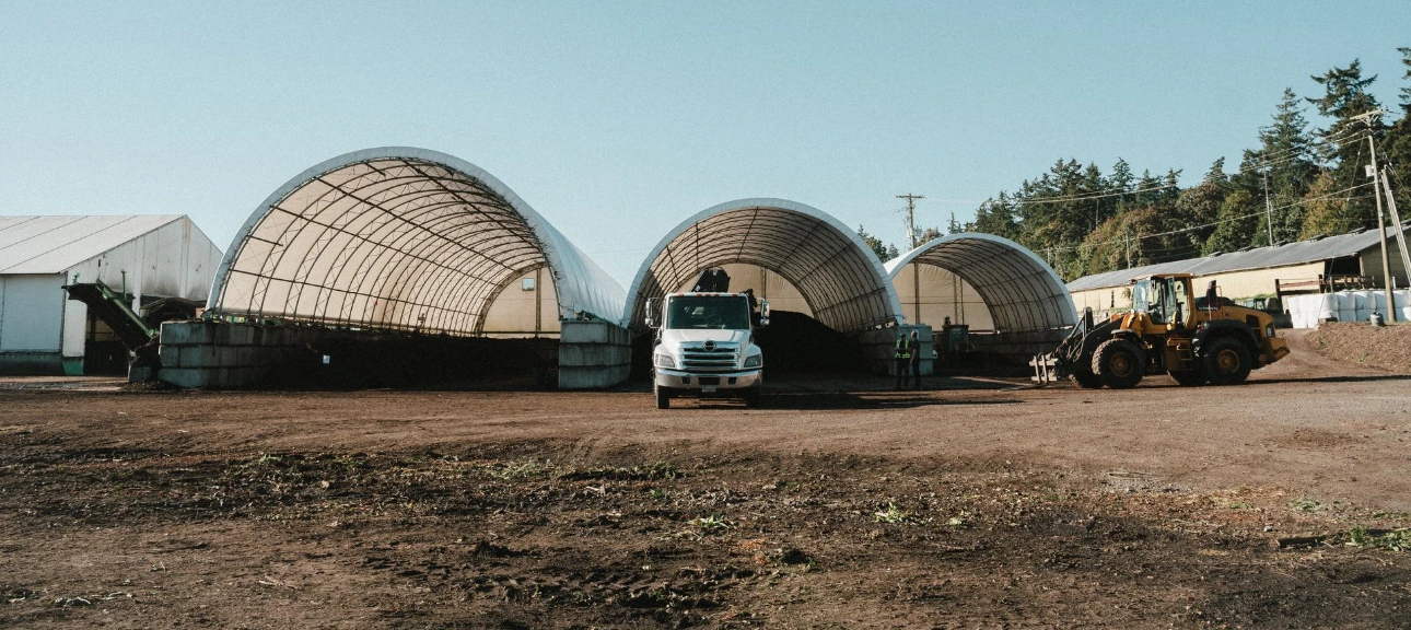 A delivery truck parked in front of large hoop house greenhouses at the Farm To Garden farm.